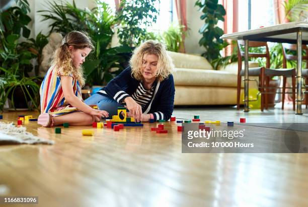 grandmother and granddaughter playing with wooden blocks at home - learning generation parent child stock pictures, royalty-free photos & images