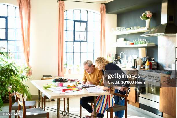 little girl colouring in at table in grandparents' home - tippspiel stock-fotos und bilder