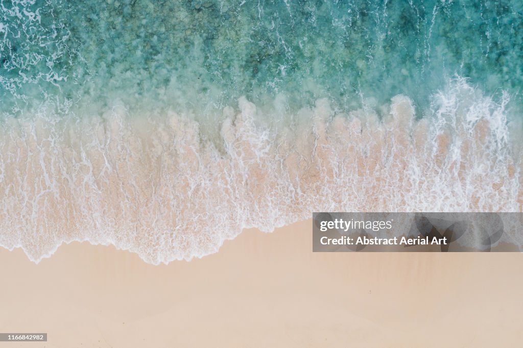 Wave textures washing onto a Caribbean beach shot from above, Barbados