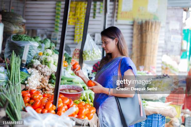 woman buying vegetables at a street vendor. stock photo - india market stock pictures, royalty-free photos & images