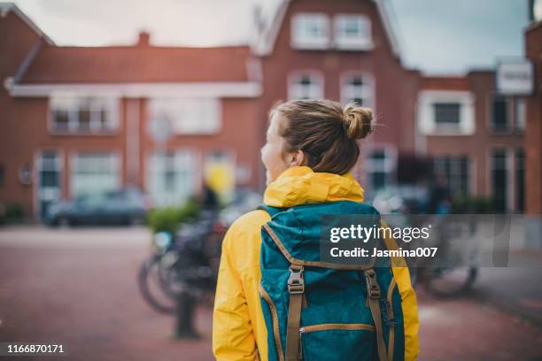 smiling student walking at the street - female rain coat stock pictures, royalty-free photos & images