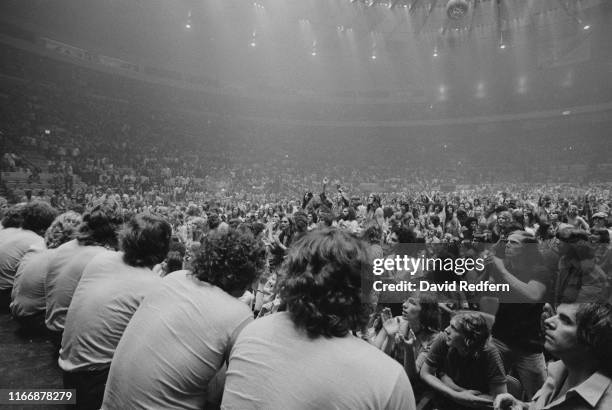 Fans and audience members watch English rock band Led Zeppelin perform live on stage on the third of three nights at Madison Square Garden, New York...