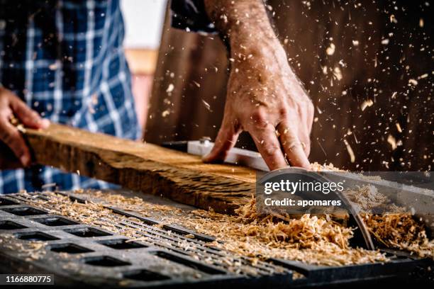 mannelijke hispanic timmerman met behulp van saw in home workshop met houtsnippers vliegen en beschermende brillen - circular saw stockfoto's en -beelden