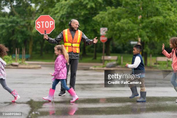 grundschüler überqueren straße mit hilfe von kreuzung wache - cross road children stock-fotos und bilder