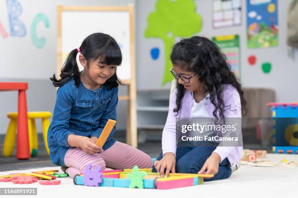 multi-ethnic group of kindergarten students building with wooden blocks - development camp stock pictures, royalty-free photos & images