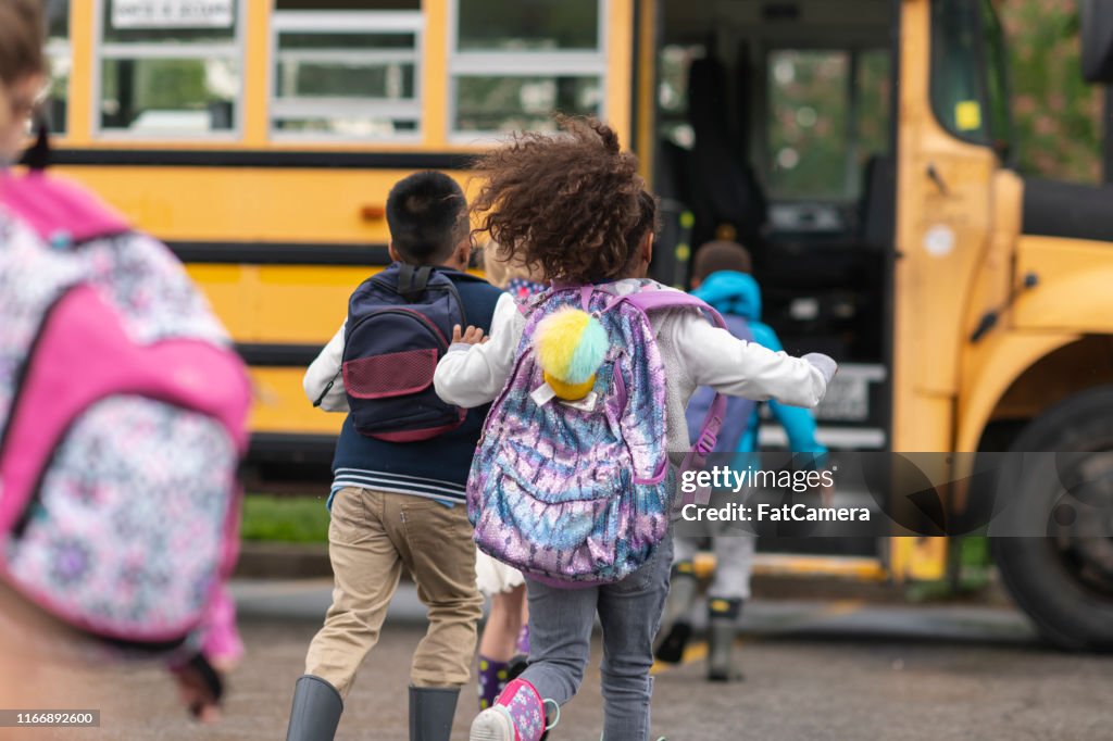 Vielfältige Gruppe glücklicher Kinder, die in den Schulbus steigen