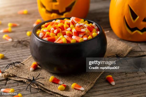 bowl of halloween candy corns and jack o' lantern - halloween candy fotografías e imágenes de stock