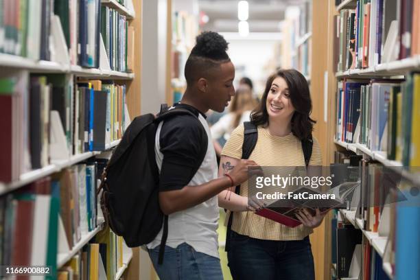 twee studenten praten in de bibliotheek - student visa stockfoto's en -beelden