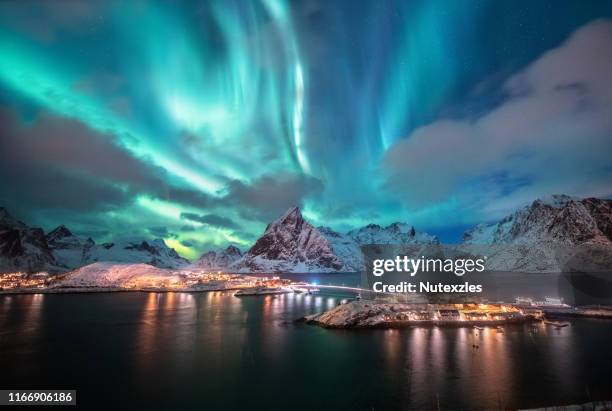 aurora borealis. lofoten islands, norway. aurora. green northern lights. starry sky with polar lights. night winter landscape with aurora, sea with sky reflection and snowy mountains. - tromso stock pictures, royalty-free photos & images