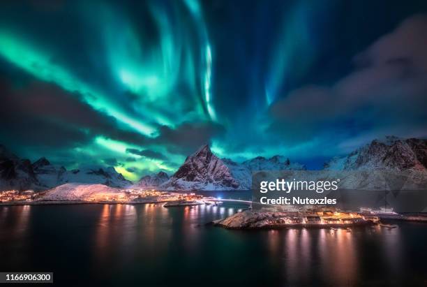 aurora borealis. lofoten islands, norway. aurora. green northern lights. starry sky with polar lights. night winter landscape with aurora, sea with sky reflection and snowy mountains. - aurora stock pictures, royalty-free photos & images