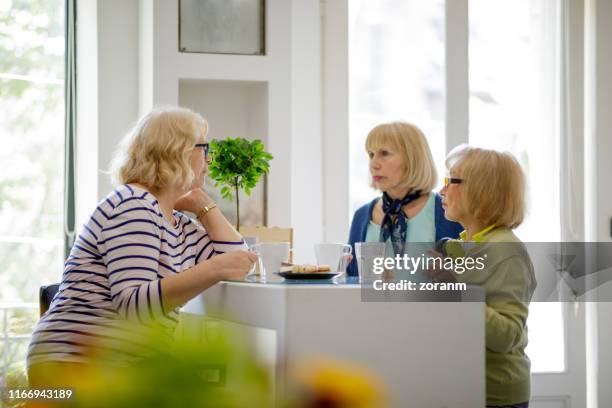 seniorinnen sprechen über ernste dinge beim kaffee zu hause - kaffeeklatsch stock-fotos und bilder
