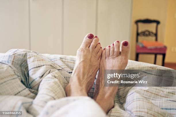 personal perspective of feet in bed - old lady feet stockfoto's en -beelden