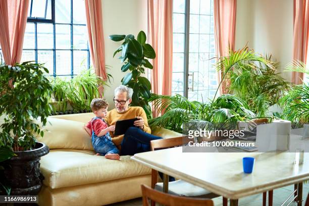 Grandfather using digital tablet with little boy