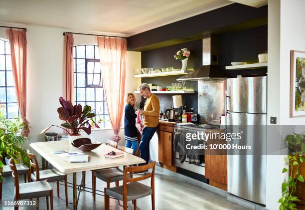 mature couple chatting in kitchen and doing the dishes - husband cleaning stock pictures, royalty-free photos & images