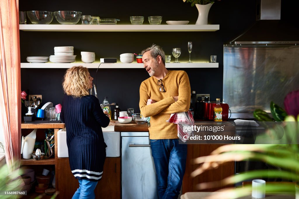 Mature man and woman doing dishes together in kitchen