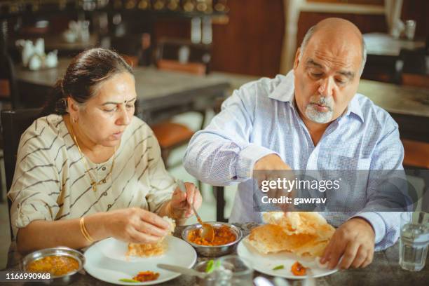 happy senior couple eats lunch together at a restaurant. - old couple restaurant stock pictures, royalty-free photos & images