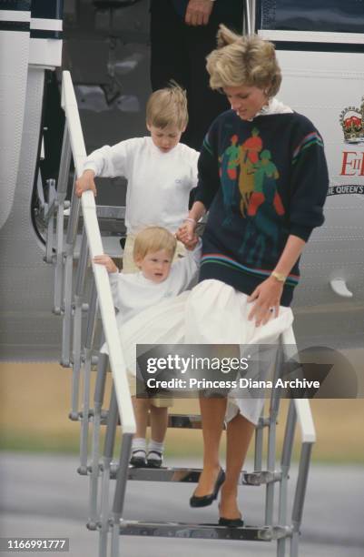 Diana, Princess of Wales arrives at Aberdeen airport in Scotland on The Queen's Flight, with her sons William and Harry, August 1986. She is wearing...