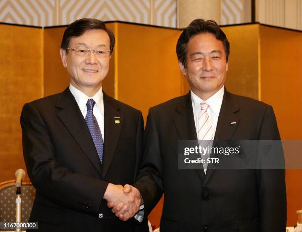 Japan's electronics giant Panasonic president Fumio Otsubo shakes hands with Sanyo Electric president Seiichiro Sano at a press conference in Osaka...