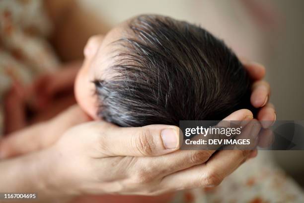 mother holding newborn baby in hands - hand in hair foto e immagini stock