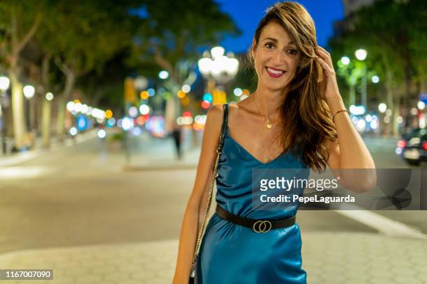 beautiful woman walking at dusk in passeig de gràcia, barcelona - satin dress stock pictures, royalty-free photos & images