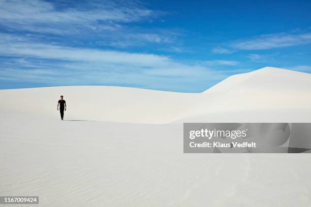 full length of young man walking on white sand at desert - paisagem árida imagens e fotografias de stock