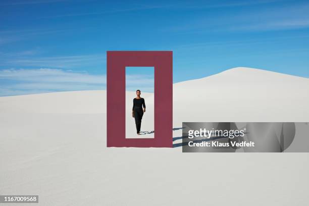 Young woman walking towards door frame on white sand dunes