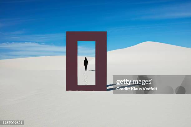 rear view of young woman walking at desert seen through door frame - solitude desert stock pictures, royalty-free photos & images