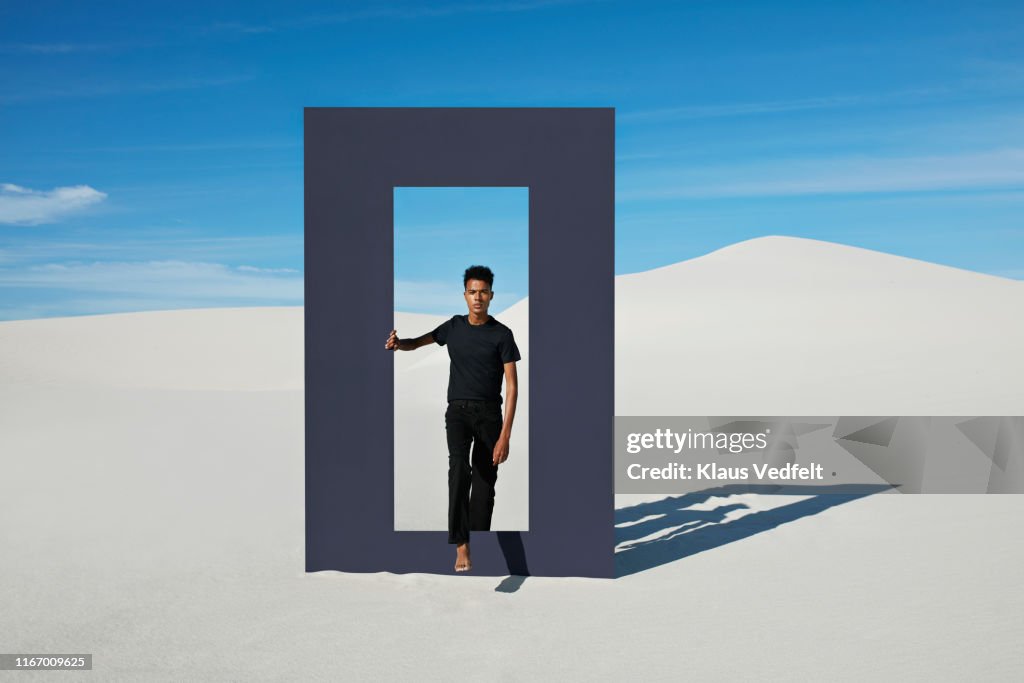 Portrait of young man walking through door frame at desert