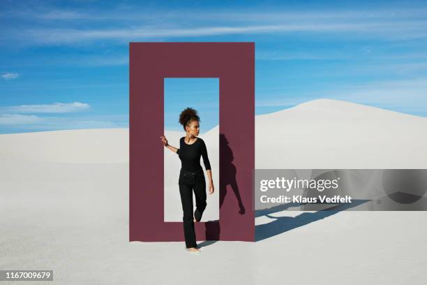 young fashion model walking through door frame at desert - white doorway stock pictures, royalty-free photos & images