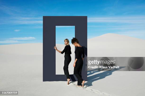 young females walking through door frame at desert - blank frame stockfoto's en -beelden