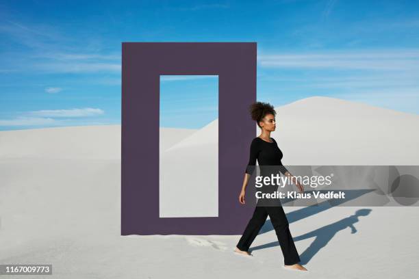 side view of young woman walking at desert during sunny day - walking into door stock pictures, royalty-free photos & images
