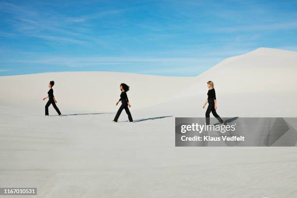 side view of female models walking at desert against blue sky - desert_climate stock pictures, royalty-free photos & images