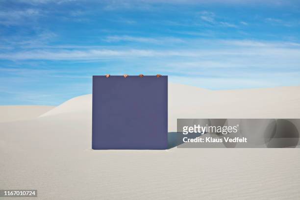 Female models holding blue portal on white sand at desert
