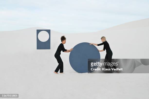 female models pushing circular portal at white desert against sky - natural change woman stockfoto's en -beelden