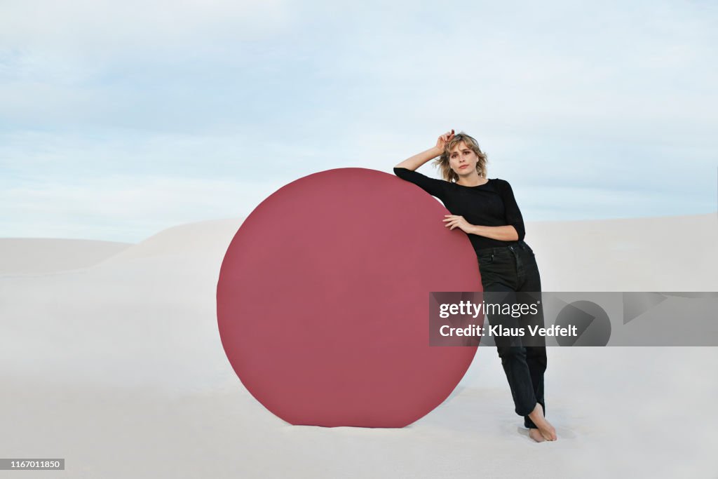 Portrait of young woman standing by circular portal at desert