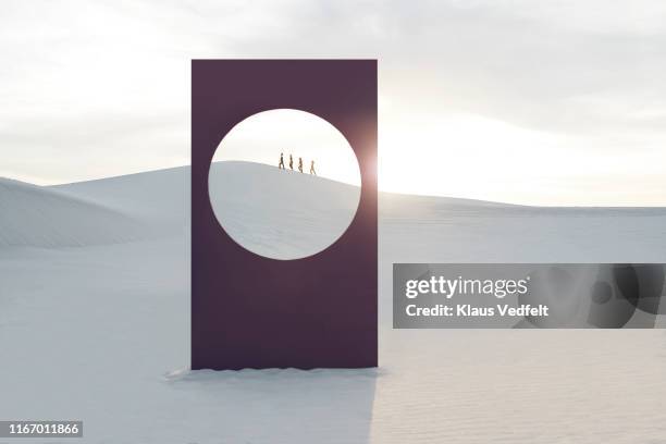 Mid distance view of female models walking at white desert seen through window frame