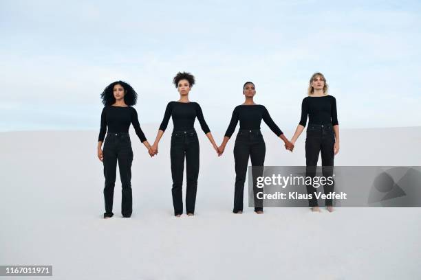young female models holding hands while walking at desert during sunset - standing together stock pictures, royalty-free photos & images