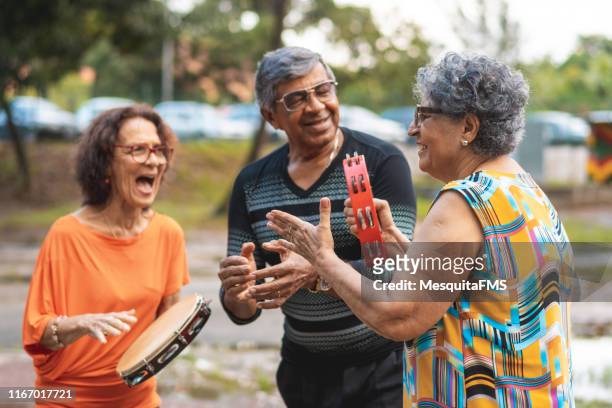 senioren spielen tamburin, singen und tanzen im öffentlichen park - fiesta latina stock-fotos und bilder