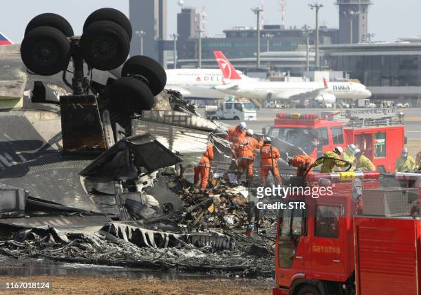 Fire fighters inspect a bunt-out FedEx cargo plane after crash landing on the runway of the Narita International Airport in Narita city in Chiba...