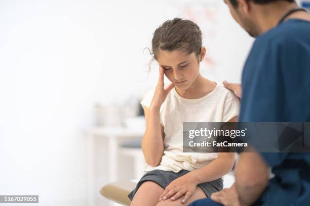 jovencita con dolor de cabeza en el consultorio del médico - headache child fotografías e imágenes de stock