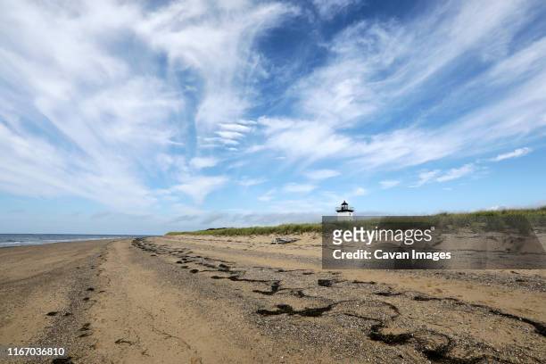 a beautiful blue sky and long stretch of sand leads to a lighthouse - cape cod bildbanksfoton och bilder