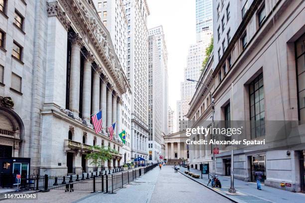 wall street and new york stock exchange in downtown manhattan, new york city, usa - wallstreet stockfoto's en -beelden