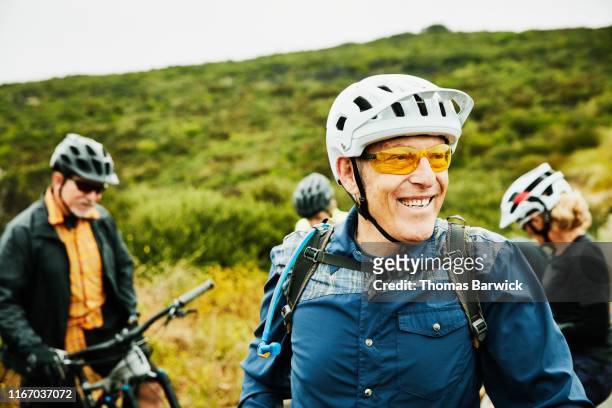 portrait of smiling senior man hanging out with friends before early morning mountain bike ride - senior adult stock-fotos und bilder