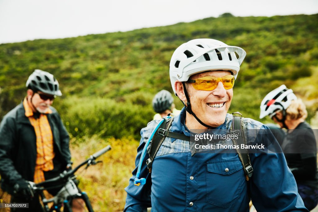 Portrait of smiling senior man hanging out with friends before early morning mountain bike ride