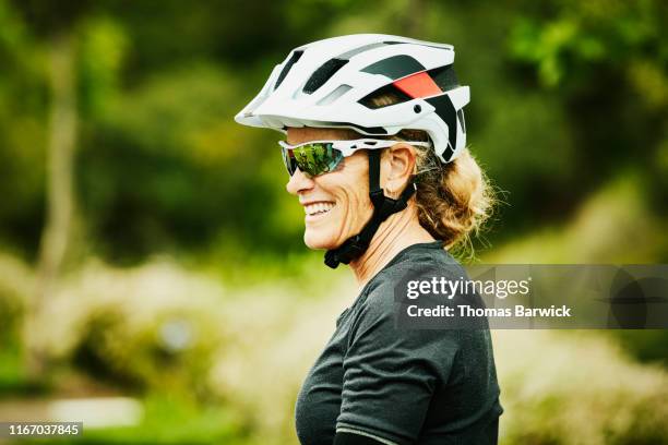 portrait of smiling mature woman relaxing after mountain bike ride with friends - cycling helmet fotografías e imágenes de stock