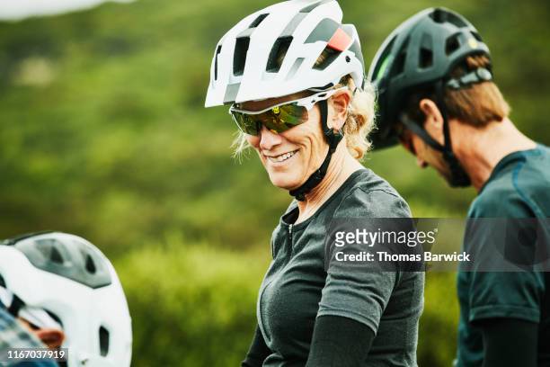 Portrait of smiling mature woman sitting on mountain bike before ride with friends