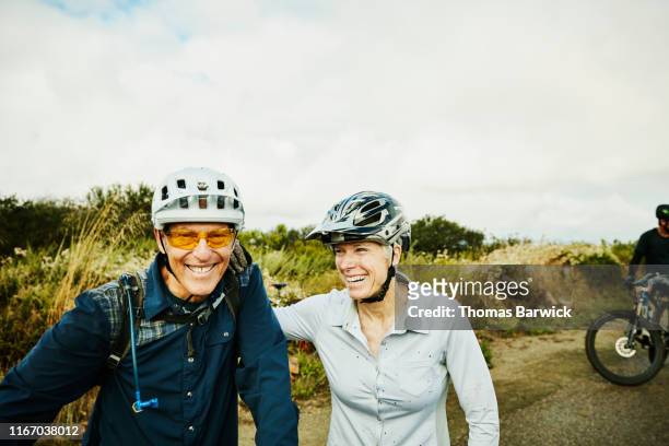Smiling senior couple resting during mountain bike ride with friends