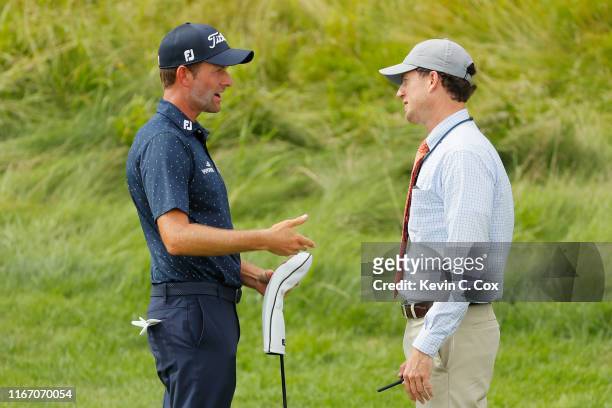 Rules official returns returns Webb Simpson of the United States his driver on the 12th hole during a suspension in play during the second round of...