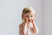 Surprised shocked child toddler girl with hands on her cheeks isolated on light background