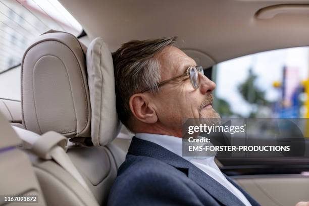 tired senior manager is relaxing in his limousine while getting chauffeured - limousine luxuswagen stock-fotos und bilder